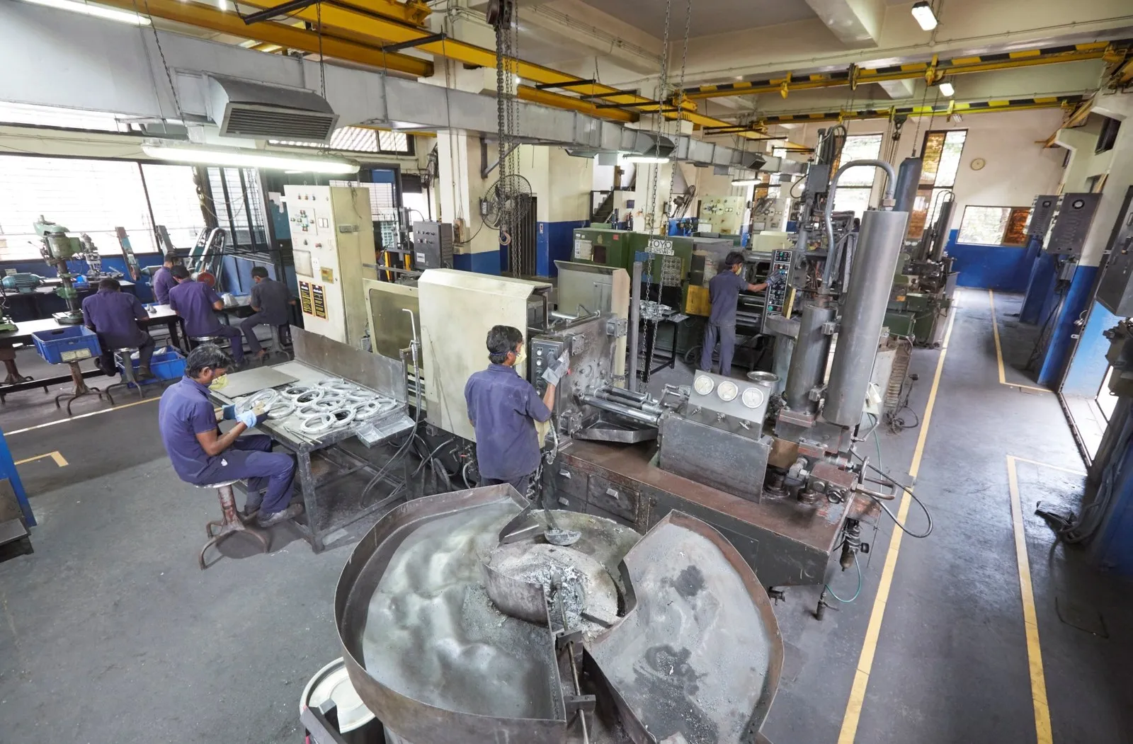 Aluminium pressure die-casting shop, with the melting furnace and trimming benches alongside the machine
